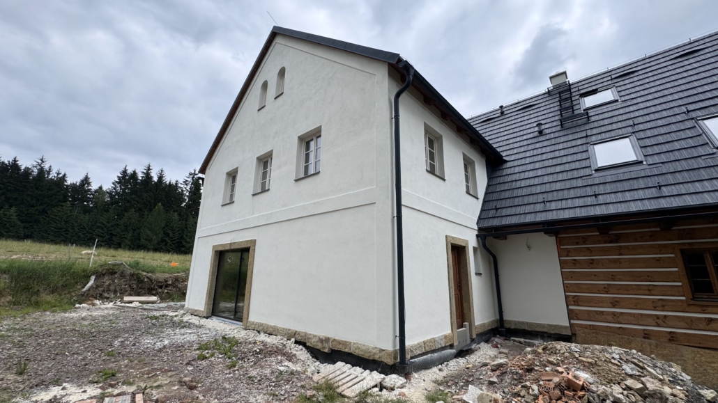 fasada libna Dokončená stavba rodinného moderního domu. Šedo-bílá fasáda s dřevěným detailem.